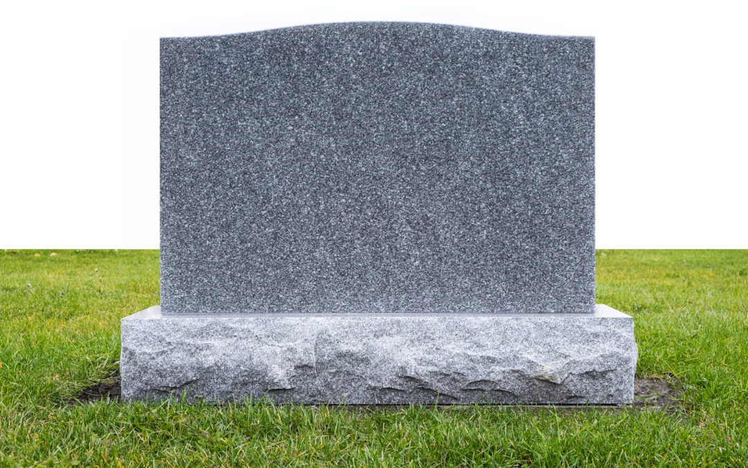 A gray stone tombstone on green grass