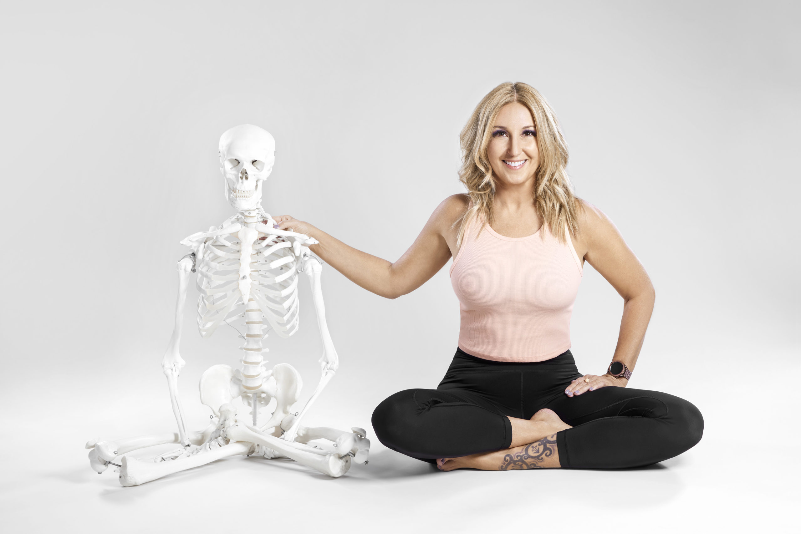 Jules siting next to a classroom skeleton with her hand on its shoulder.