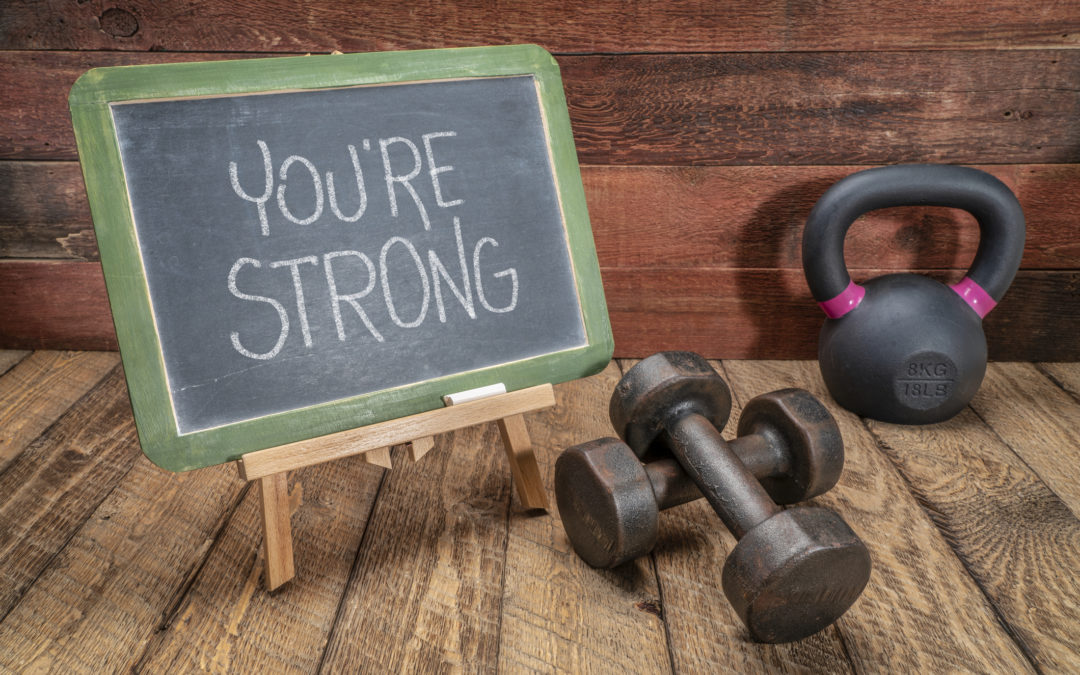 "you're strong" on a chalkboard surrounded by a kettlebell and dumbells